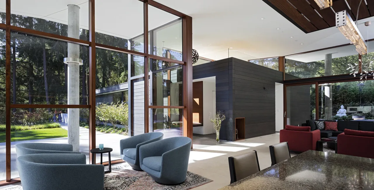 Living area featuring wood-framed large windows, a mix of modern seating, and views of the outdoors with natural light filling the space.