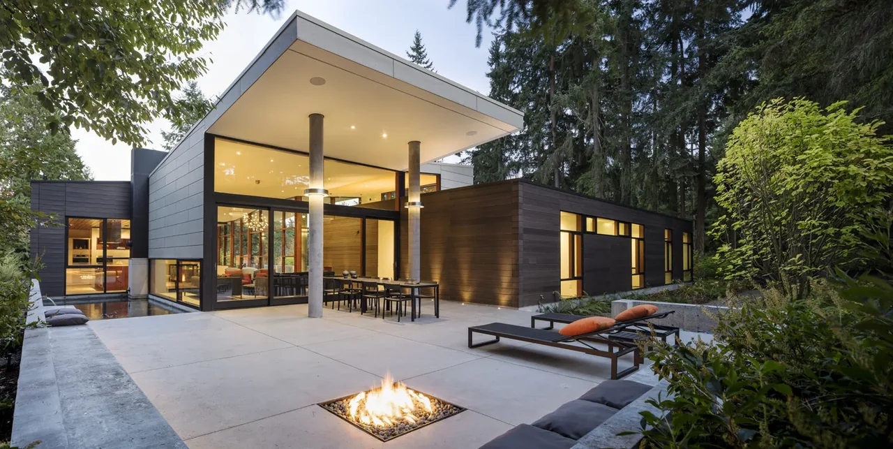 Exterior view of the Inside Outside House featuring a covered patio with seating, fire pit, and expansive glazing.