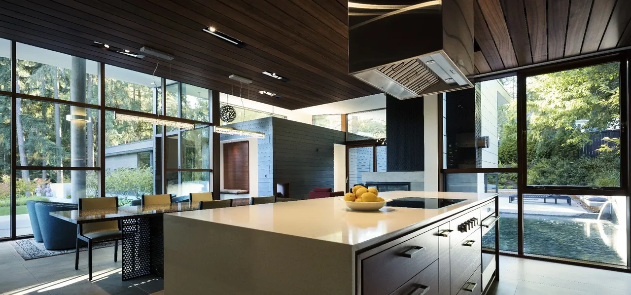 Kitchen and dining space with large grid window framing and a view of the outdoor water feature and greenery.