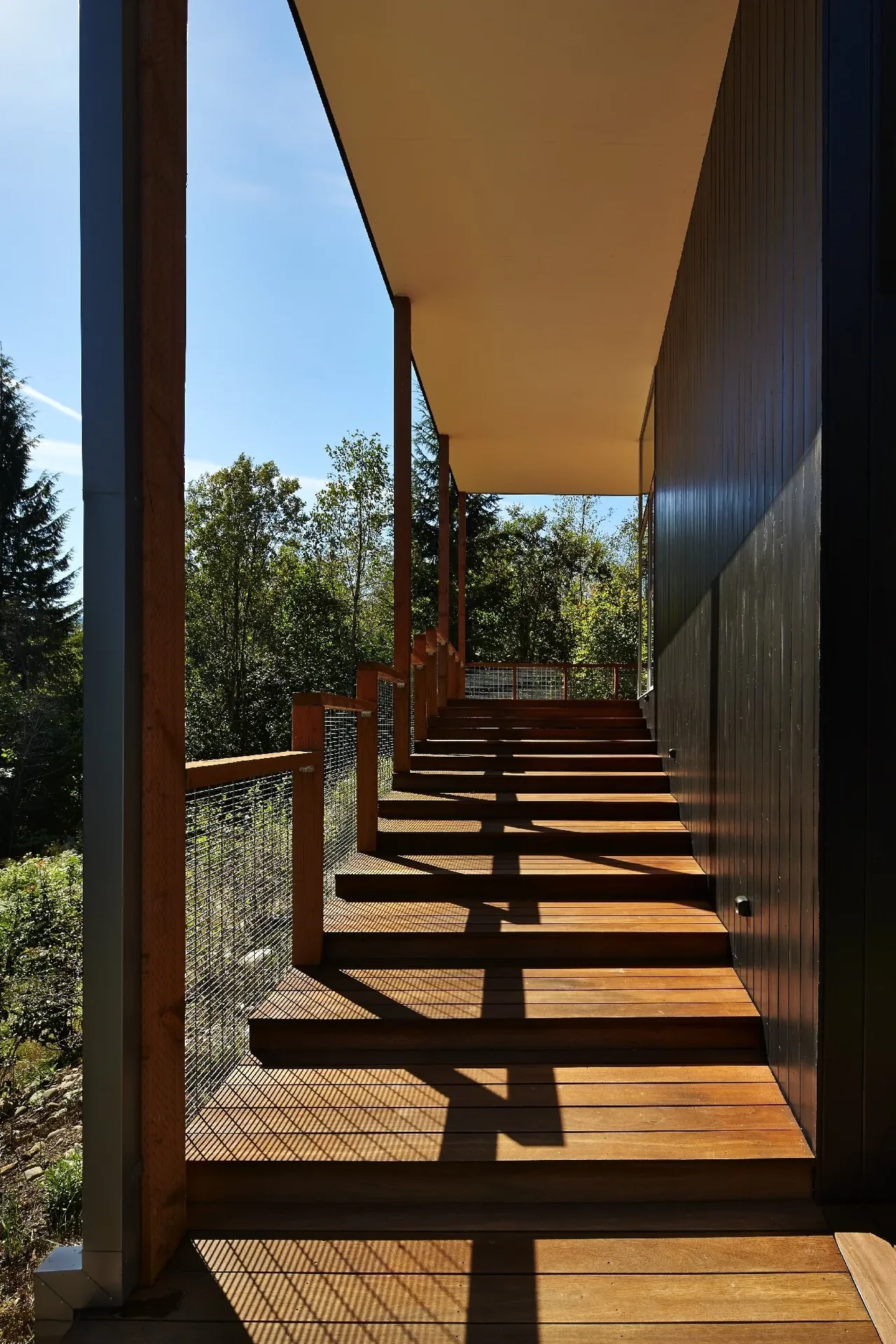 Exterior stairway with wood steps and metal mesh railing under a covered roof at Bear Run Cabin.