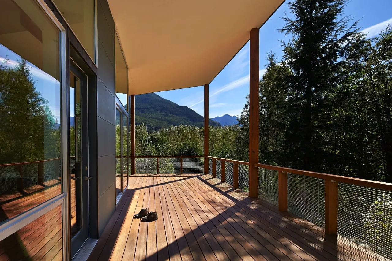 The Bear Run Cabin features a wooden deck with metal mesh railing offering views of forest and mountains.