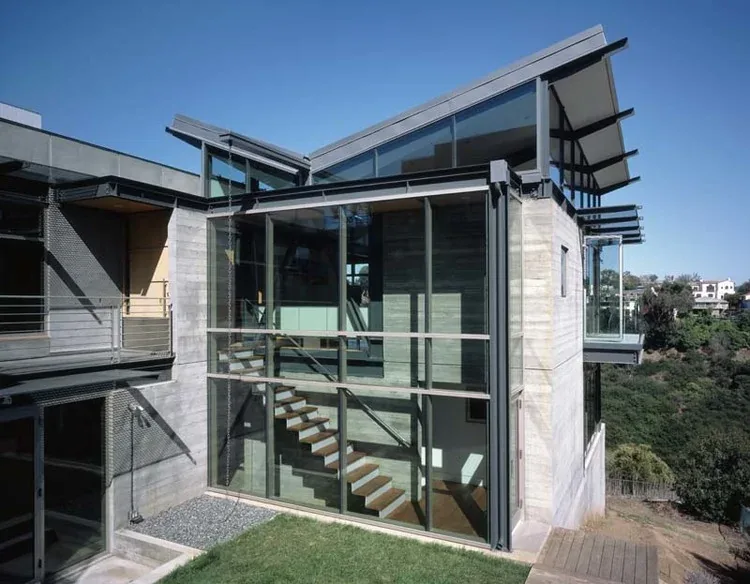 Grenola Malibu Residence by David Gray Architects features angular rooflines and extensive glass façades showcasing a suspended wooden stair.