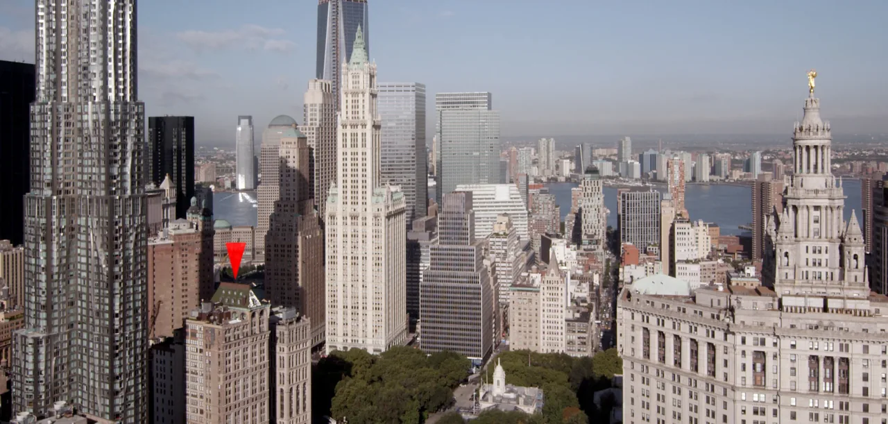 View of a dense urban skyline with various high-rise buildings and a river beyond them.