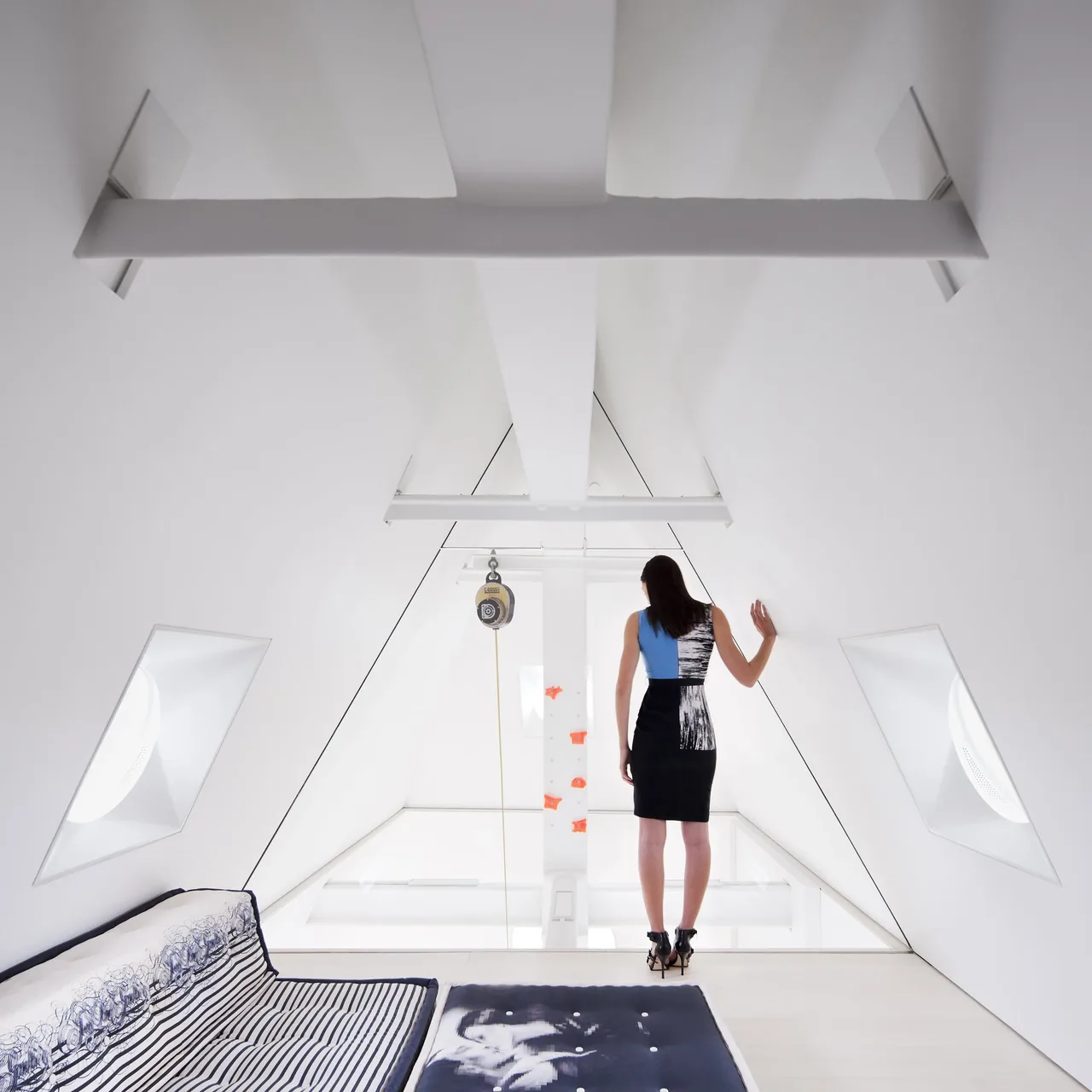 Interior attic space with a vaulted ceiling, white finishes, and two oval windows on angled walls.