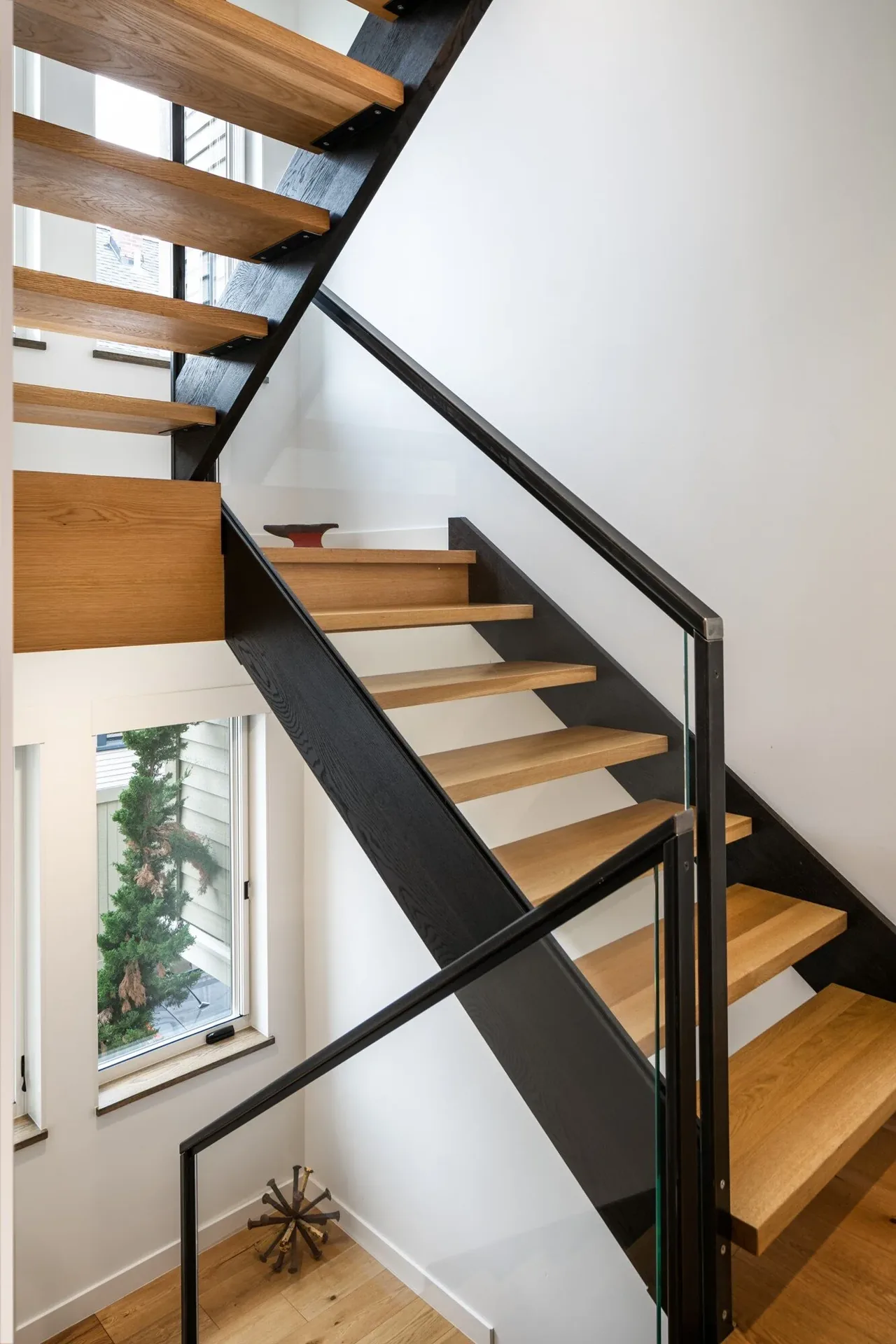 Open riser staircase with oak treads and black metal support and railing with glass panels at E Denny Way Townhouse Renovation.