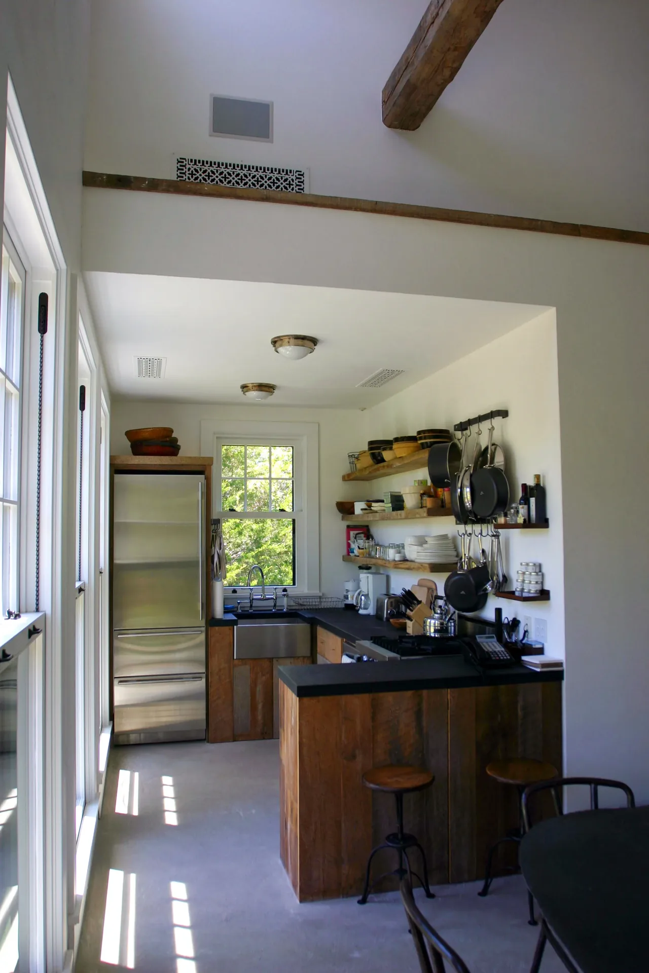 Montauk Guest Cottage kitchen features rustic wood cabinetry, open shelving, and modern appliances with abundant natural light.