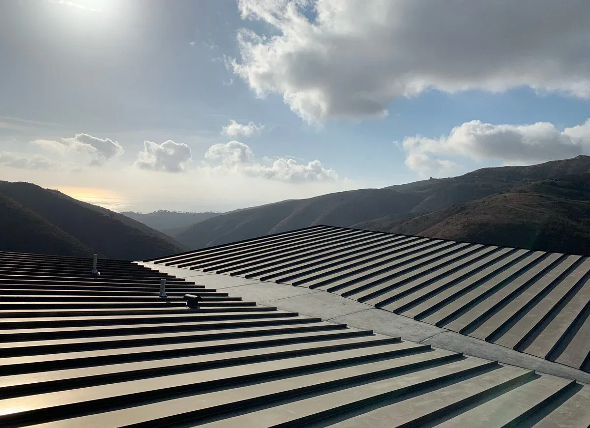 Metal standing seam roof on a hillside home with views of the mountains and distant ocean at Yerba Buena Residence III.