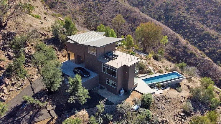 Yerba Buena Residence III is a hillside modern home with a flat standing seam metal roof and rectangular infinity pool.