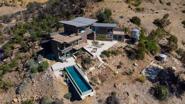 Yerba Buena Residence III features a modern metal exterior with a cantilevered pool amid natural hillside terrain.