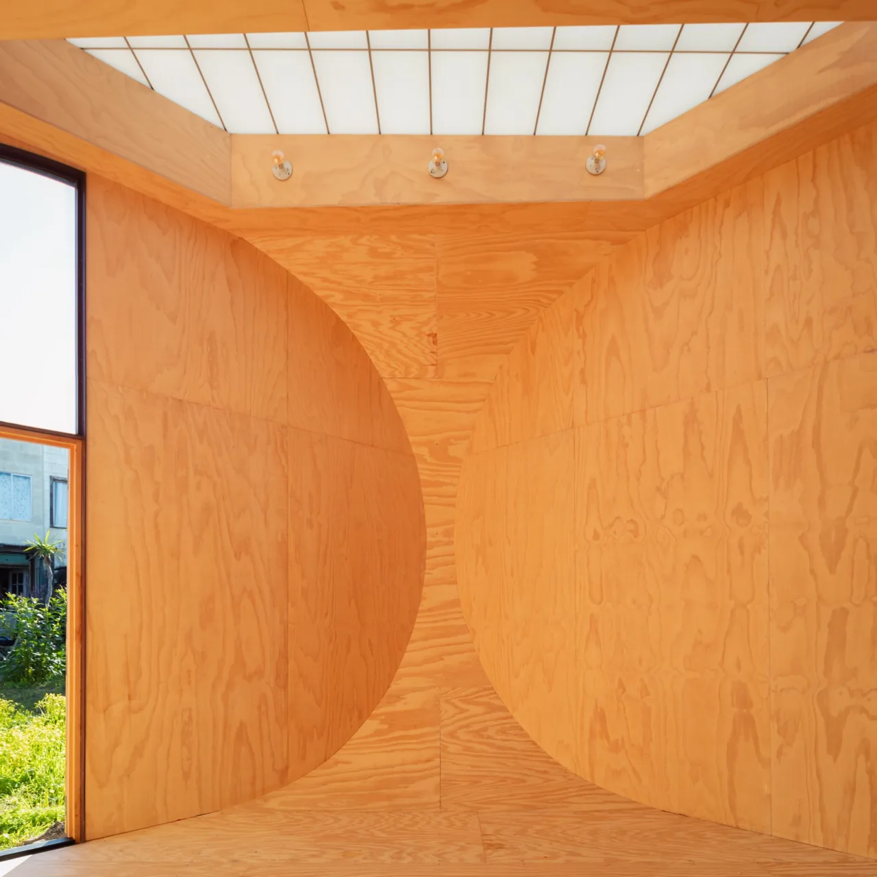 Interior view showing curved plywood walls and a translucent ceiling in The Sandtrap project.