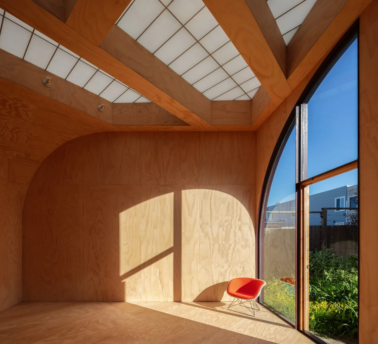 The Sandtrap features an interior with plywood walls, a large curved window, and ceiling panels that diffuse natural light.
