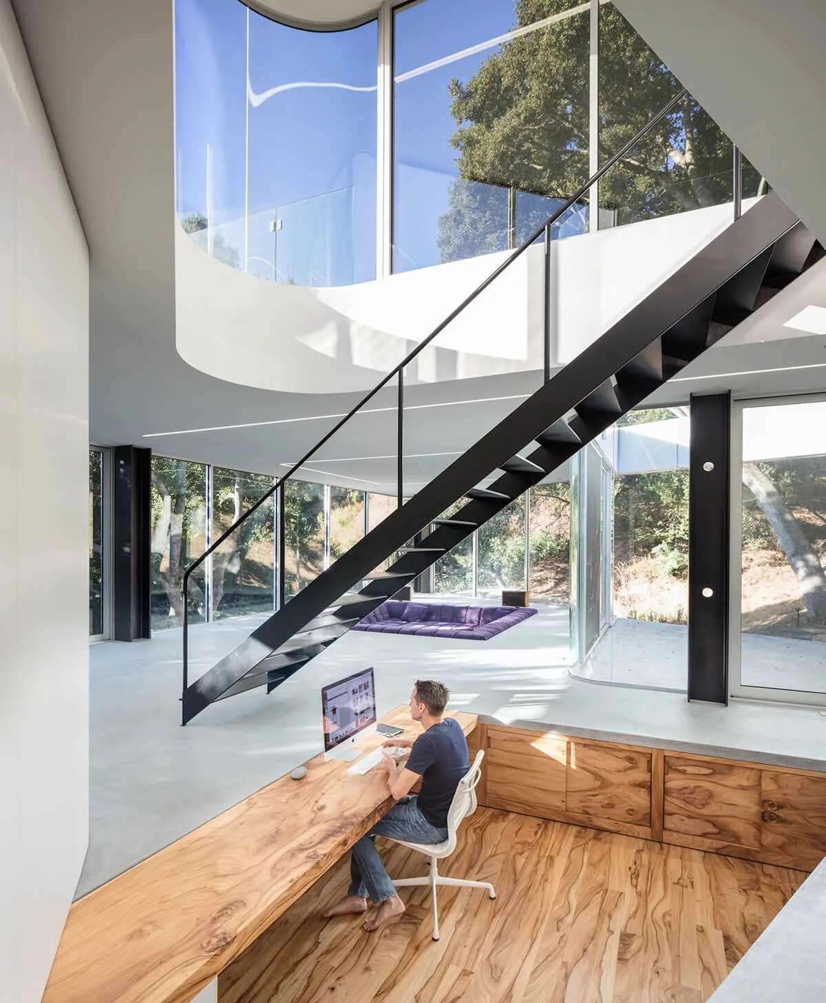 Pam & Paul's House features a modern office with a curved glass corner window and floating black steel staircase.