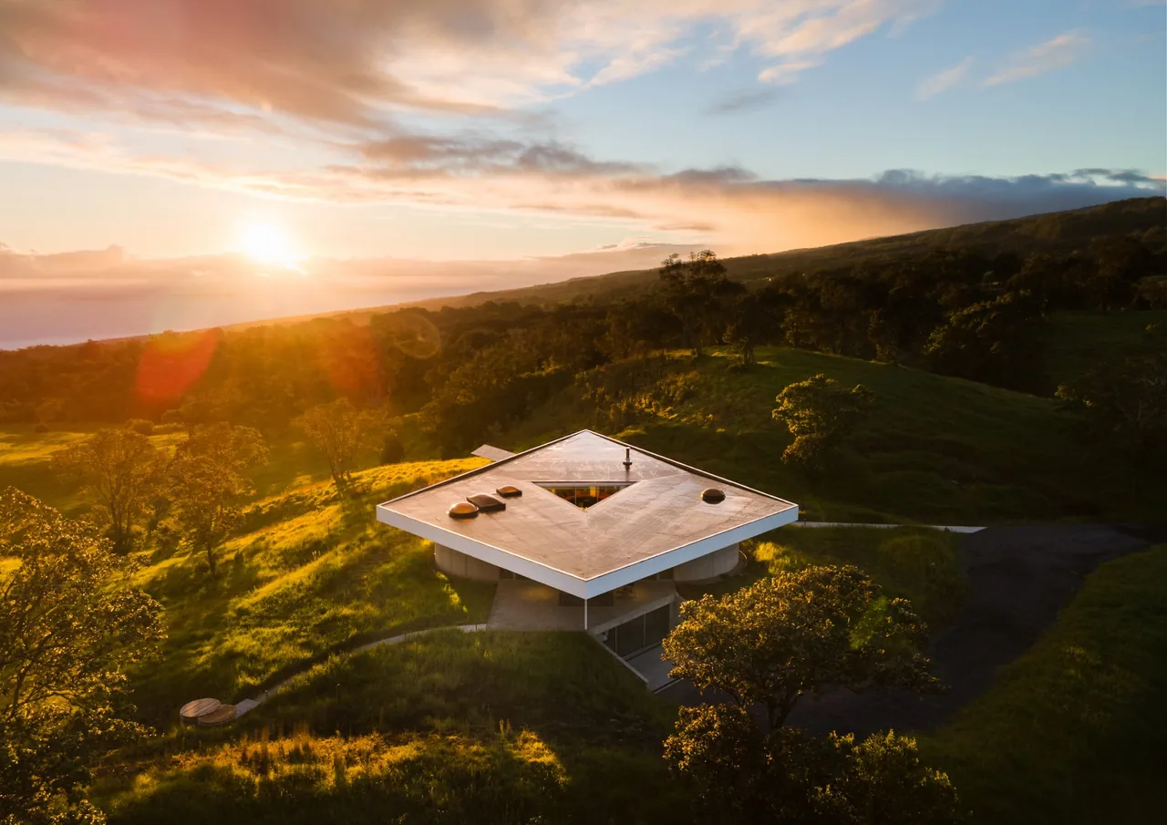 The Musubi House features a flat roof with a central courtyard, situated on a hillside with natural landscape.