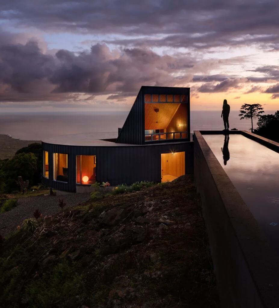 D Fin House features a curved form, sloped wood ceiling, and a reflective pool above an upland coastal site.