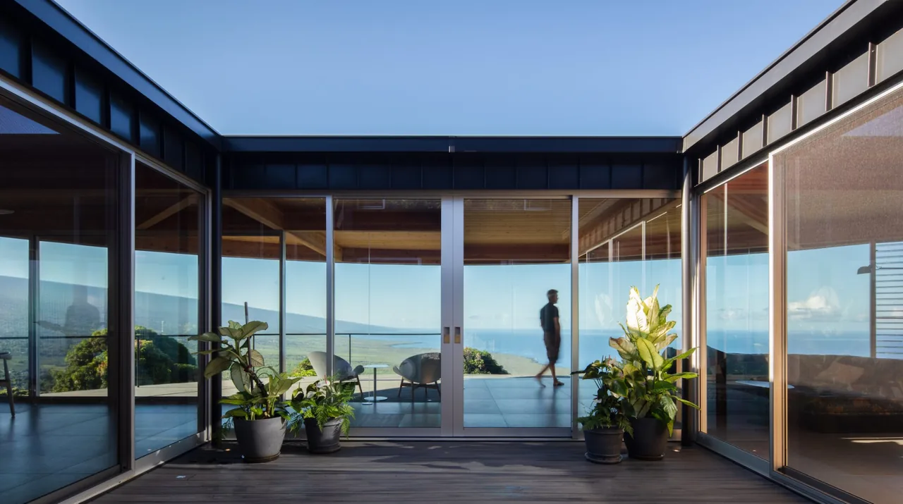D Fin House courtyard with floor-to-ceiling glazing and sliding glass doors opening to panoramic outdoor views.