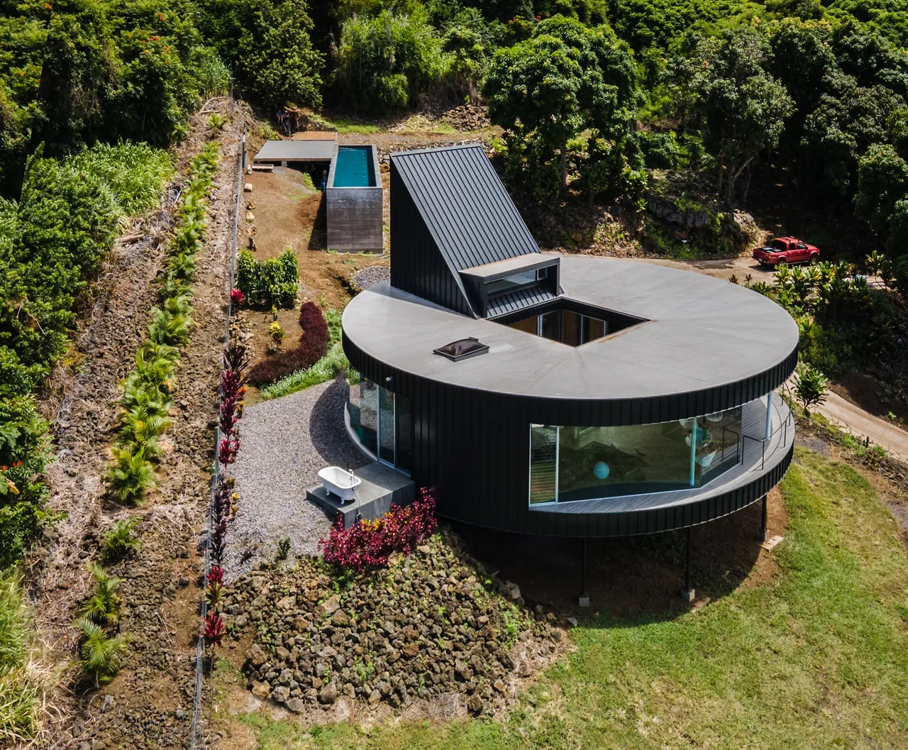 D Fin House features a circular plan with a sloped roof element, located on an upland coastal site.
