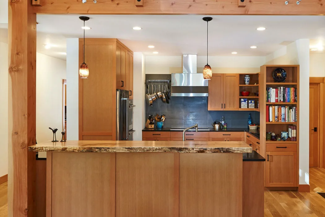 Kitchen featuring wooden cabinets, a natural edge island countertop, stainless steel appliances, and pendant lights.