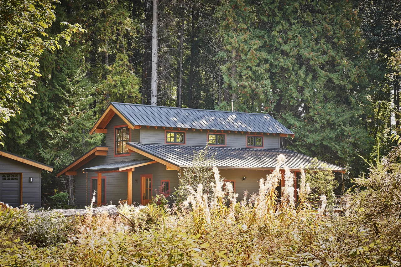 Bainbridge Island Farmhouse features a multi-level metal shed roof and natural wood trim in a wooded setting.