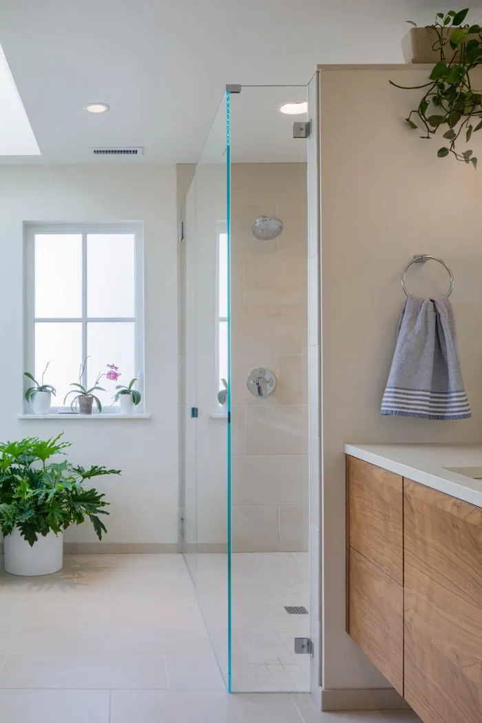 Bathroom featuring a walk-in shower with frameless glass door and a natural wood floating vanity.