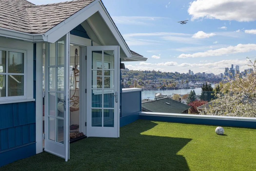 Rooftop deck in an urban farmhouse with artificial turf providing a green play area and city skyline views.
