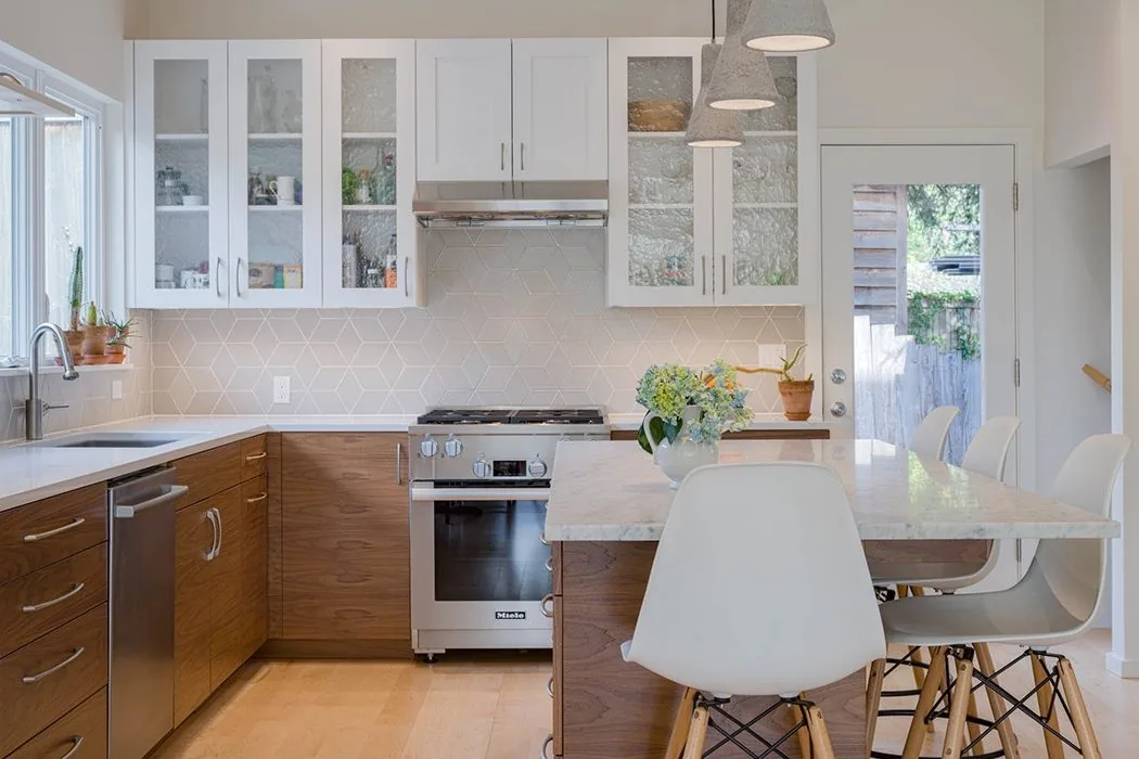 Urban Farmhouse kitchen features wood cabinets, white upper glass cabinets, and a marble island with pendant lighting.