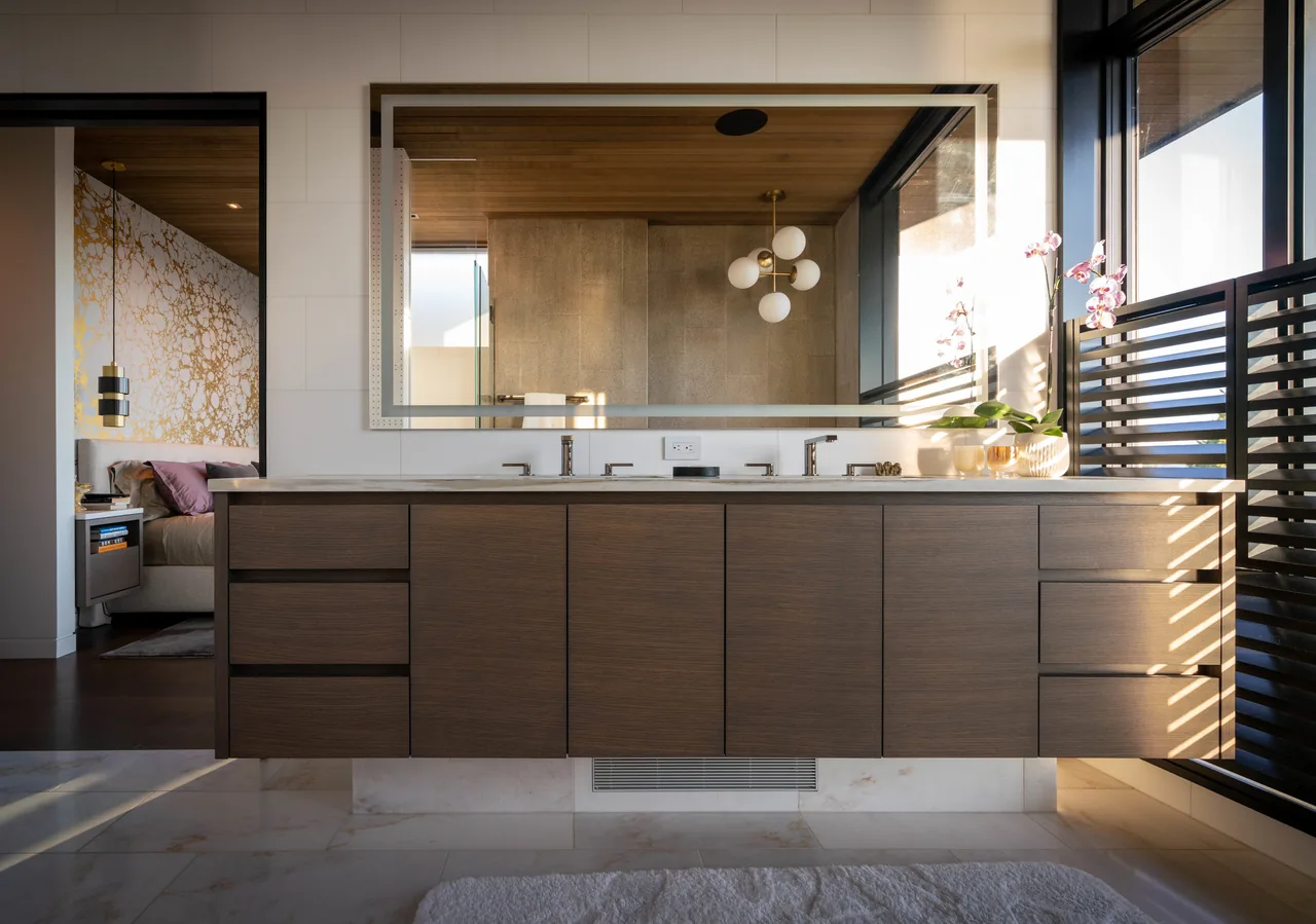 Floating double vanity with wood cabinets and double undermount sinks beneath a large framed mirror in a modern bathroom.