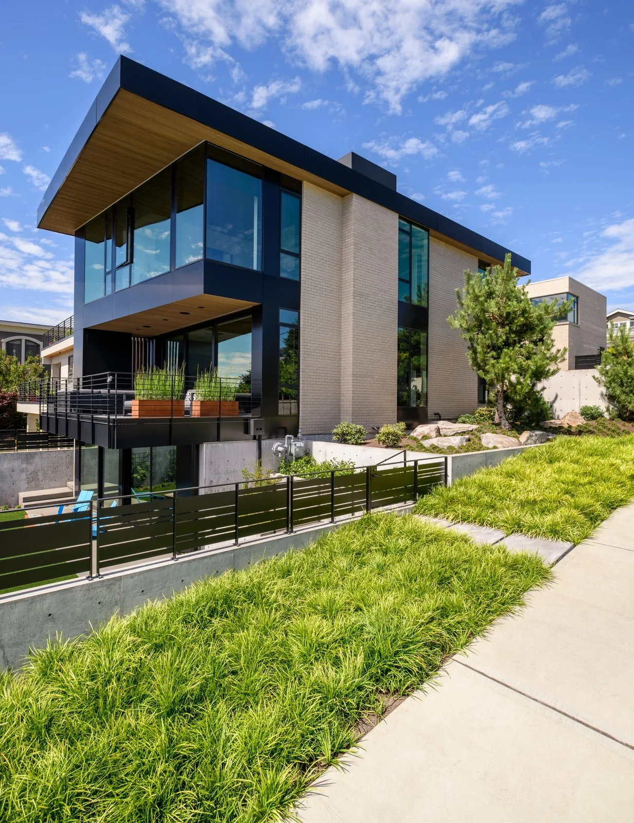 West of Market house by Sticklab Architecture features multi-level terraces with concrete retaining walls and metal railings on a sloped site.