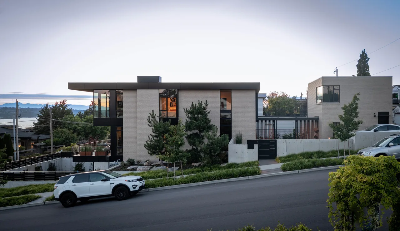 West of Market project by Sticklab Architecture features a modern two-story home with brick, large windows, and a concrete retaining wall.