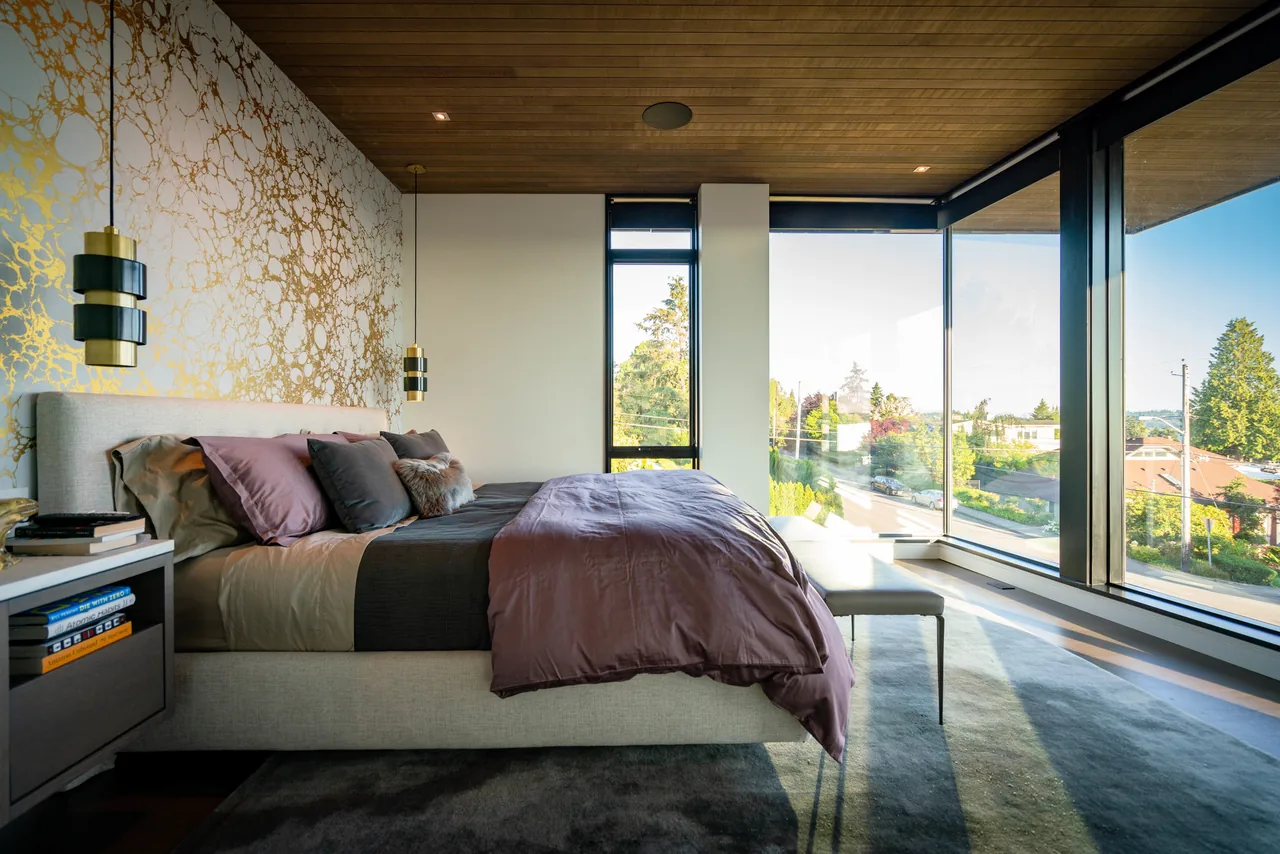 Bedroom in West of Market project with floor-to-ceiling corner windows and a decorative gold-patterned accent wall by Sticklab Architecture.
