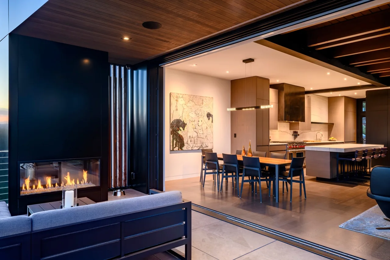 The West of Market project features an open kitchen and dining area connected to an outdoor living space with a linear fireplace and recessed lighting.