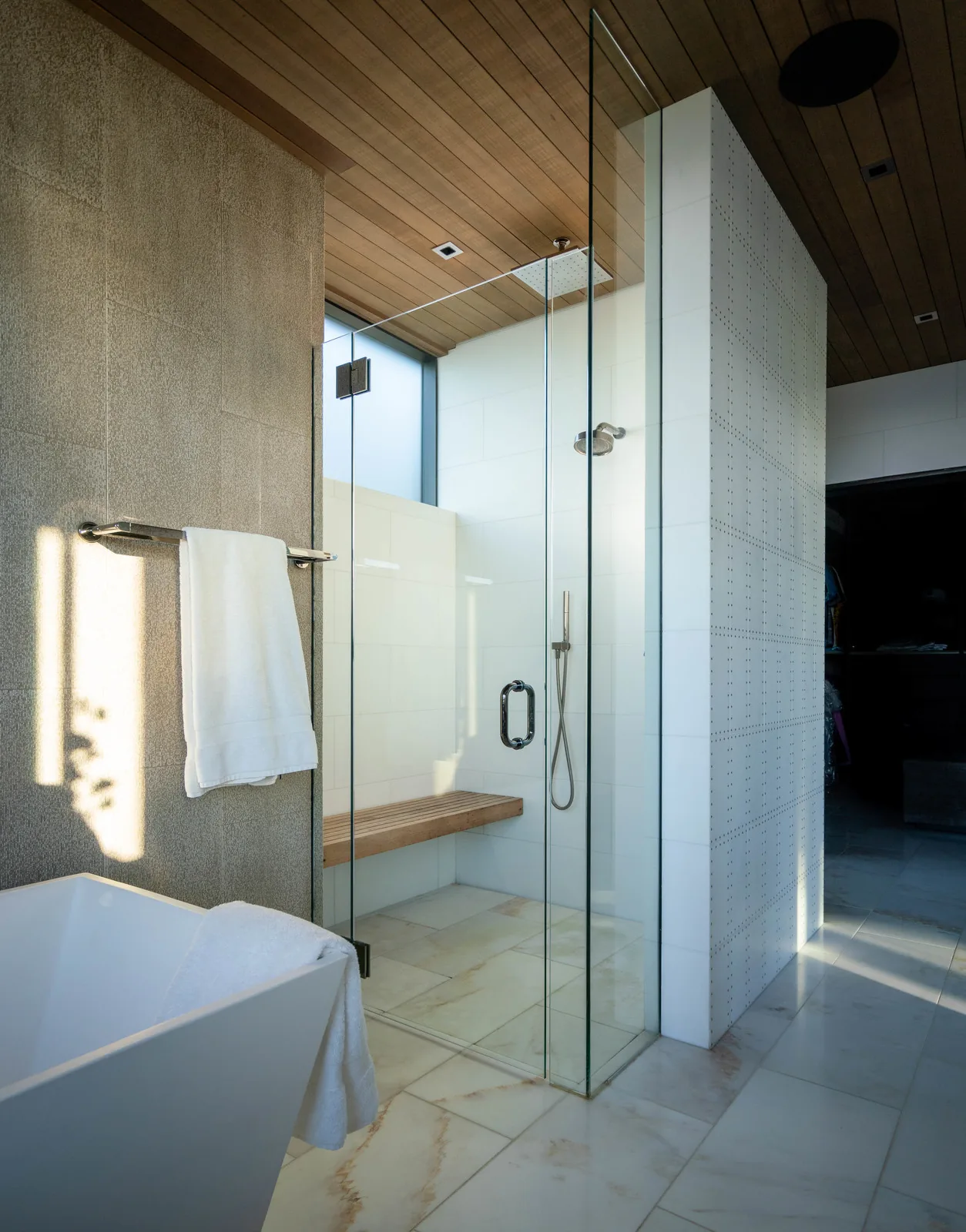 Bathroom interior highlighting a glass shower enclosure with built-in wooden bench and rain showerhead.