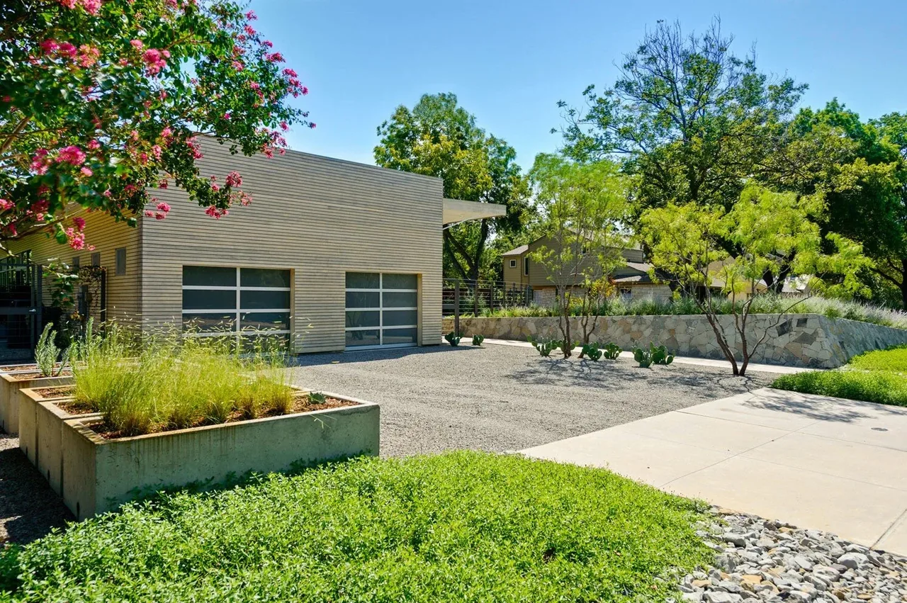 Pomona Residence features wood siding with a concrete retaining wall and a gravel driveway.