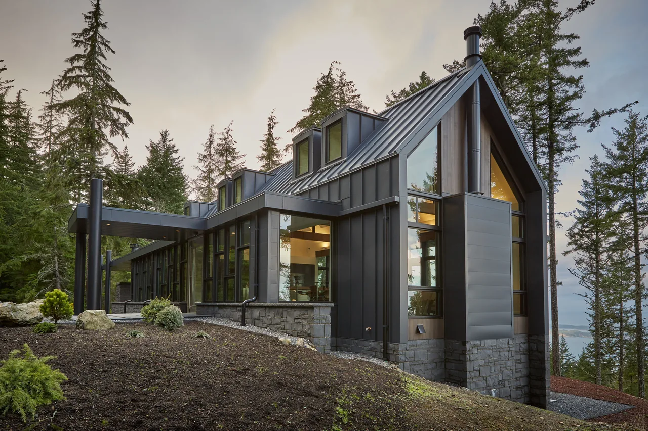 Buck Mountain Residence features metal siding, large windows, and sits in a forest setting near Seattle.