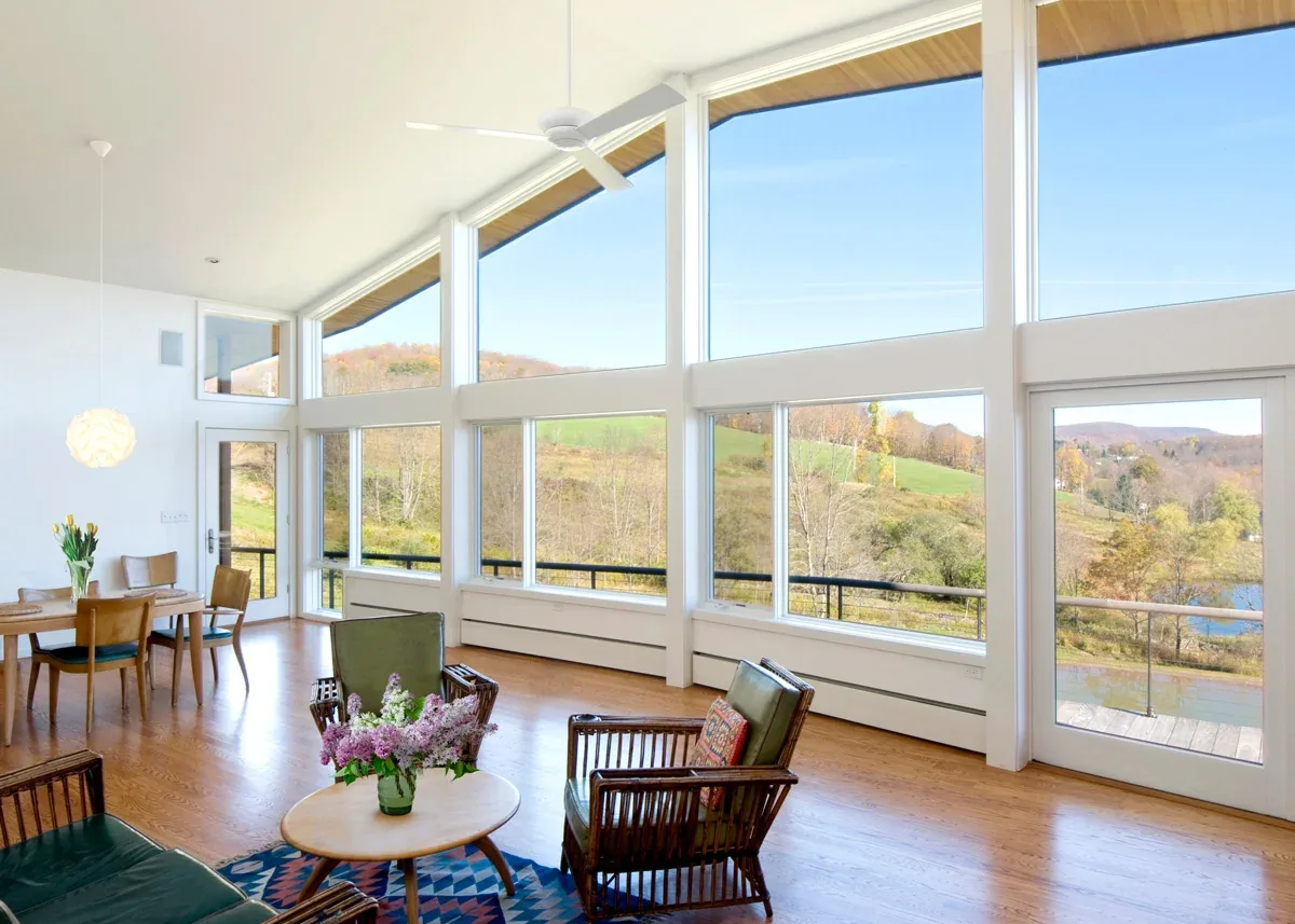 Quail Ridge House features expansive floor-to-ceiling glazing with views of hills and a pond from the open living and dining space.