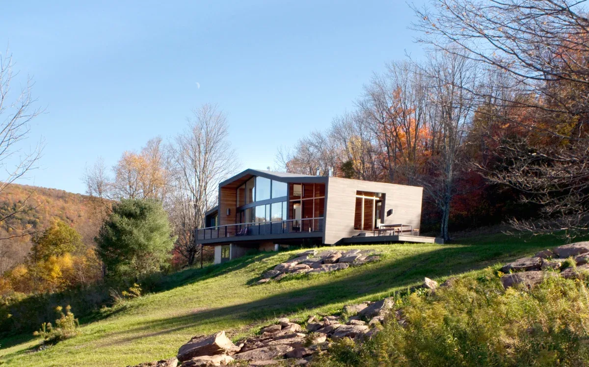 The Quail Ridge House by David Weiner Architects sits on a hillside with expansive glazed facades and a wood exterior.