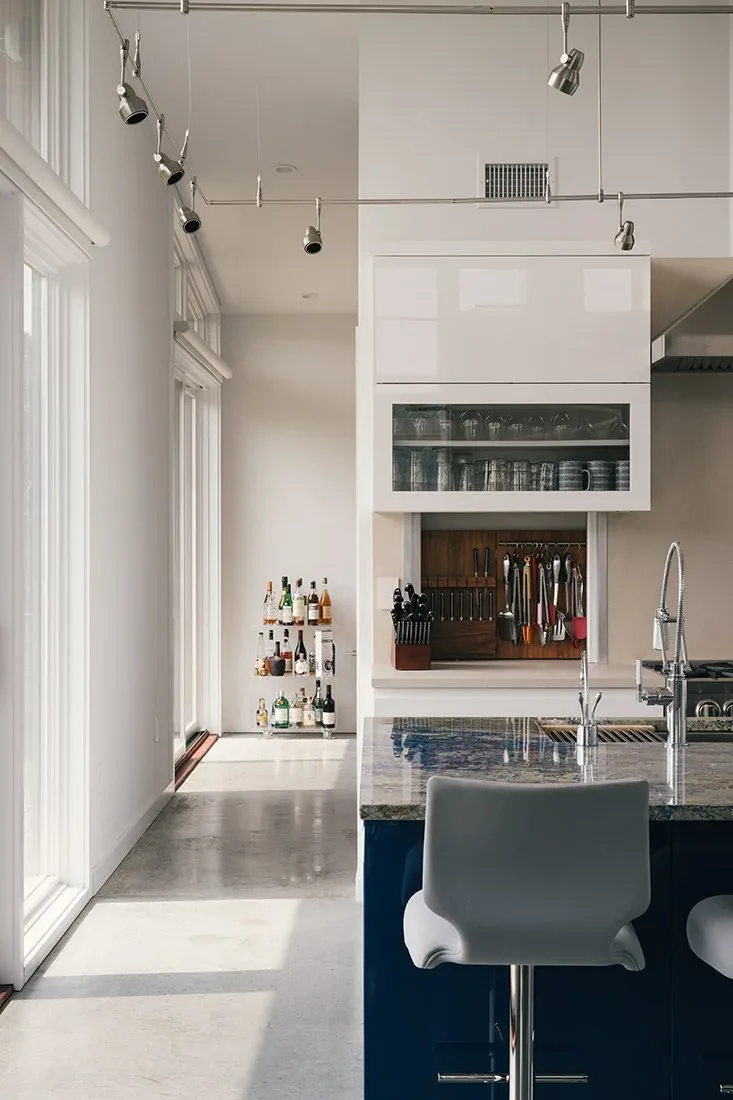A kitchen featuring a granite island with two bar stools and a wall-mounted storage area for kitchen utensils.
