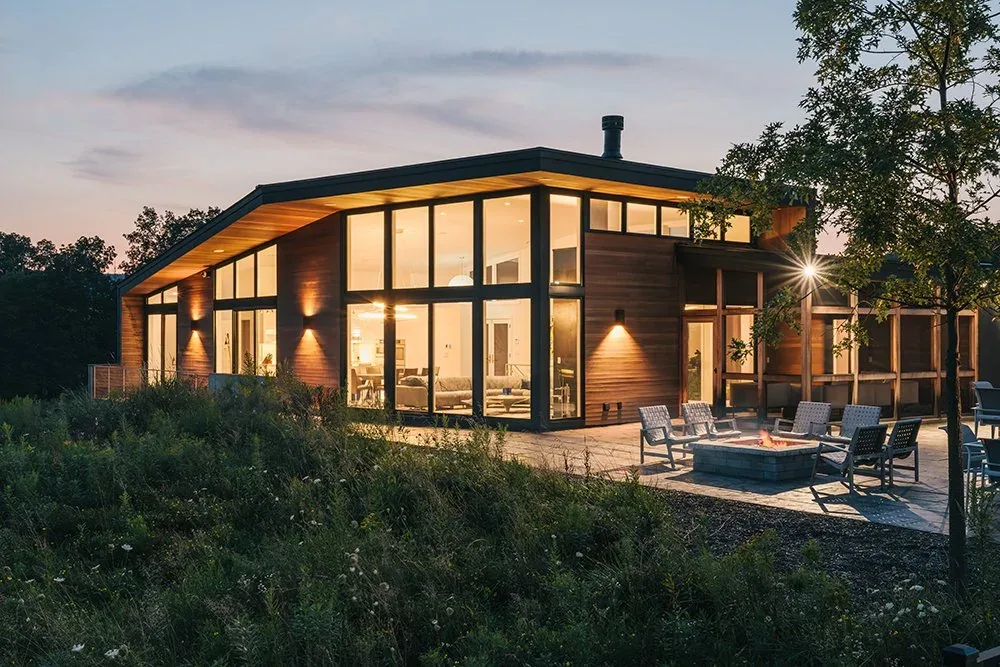 The Rolling Meadow House features wood panel siding and extensive glazing with a modern low-pitched roof.