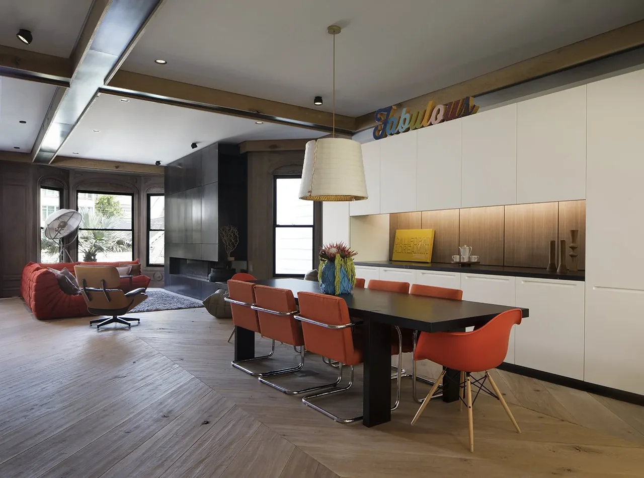Open dining and living area featuring a black dining table with orange chairs and a black built-in fireplace.