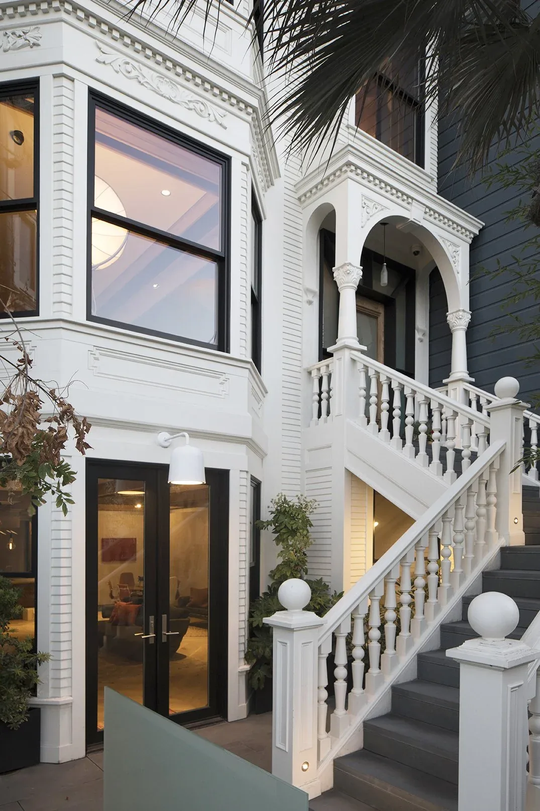 Traditional-style house exterior with white detailed trim, black window frames, and a white staircase with balusters.