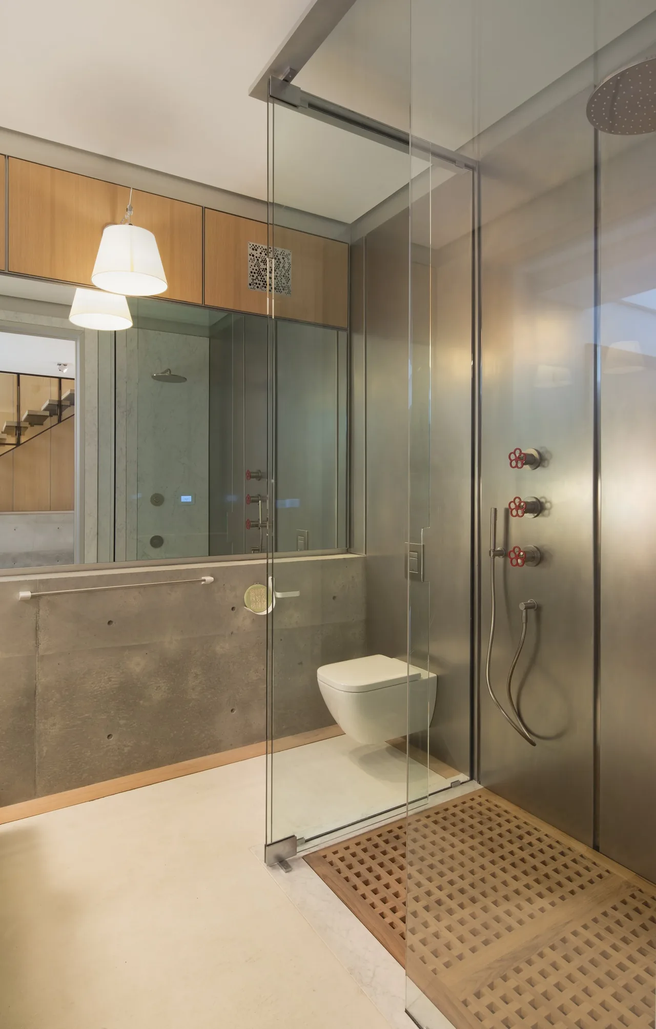 Bathroom features concrete wainscoting with wood paneling, a wall-mounted toilet, and a glass-enclosed shower with minimalist fixtures.
