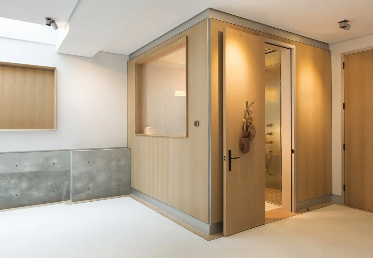 Minimal hallway features light wood paneling and a visible walk-in shower with modern fixtures.