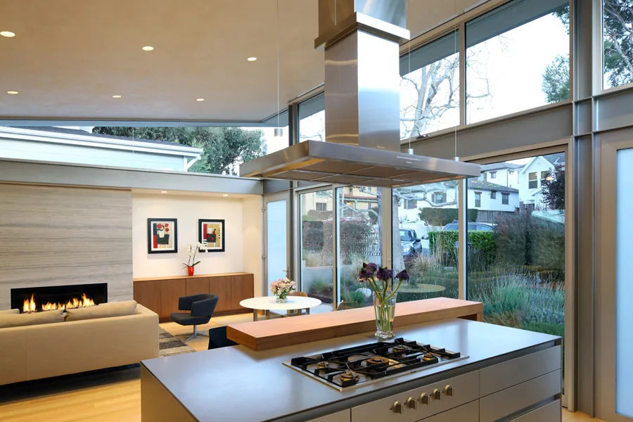 Open floor plan with kitchen island featuring a gas range and a living room with a fireplace and large windows.