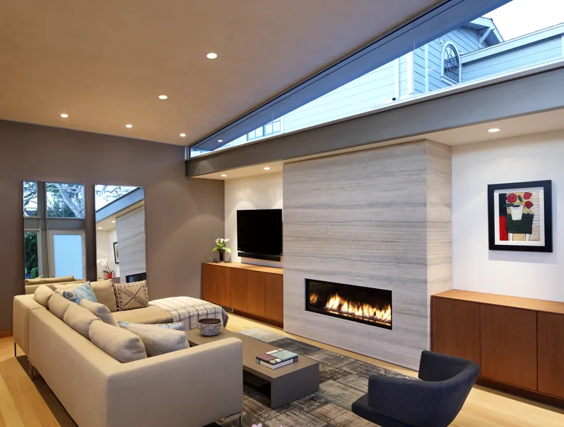 Living room features a linear fireplace with a stone facade, beige sectional sofa, and clerestory windows for natural light.