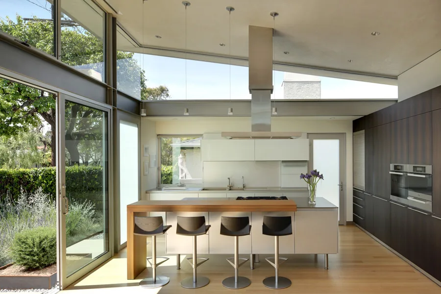 Kitchen in the Madans project with glass sliding doors, clerestory windows, and natural wood flooring.