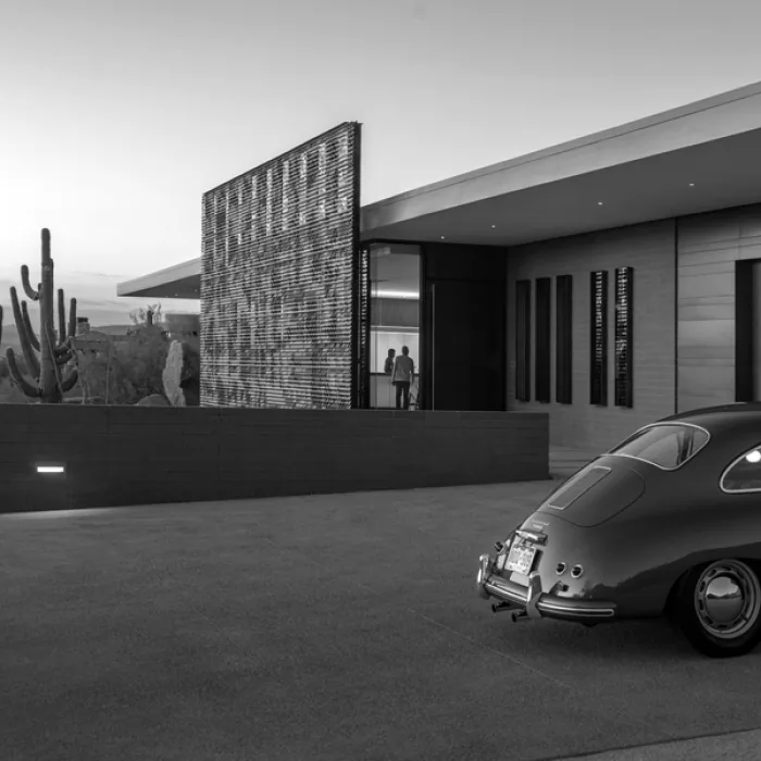 Desert Platform house in Phoenix features a flat roof and a vertical wood slat screen near the entrance with a classic car parked outside.