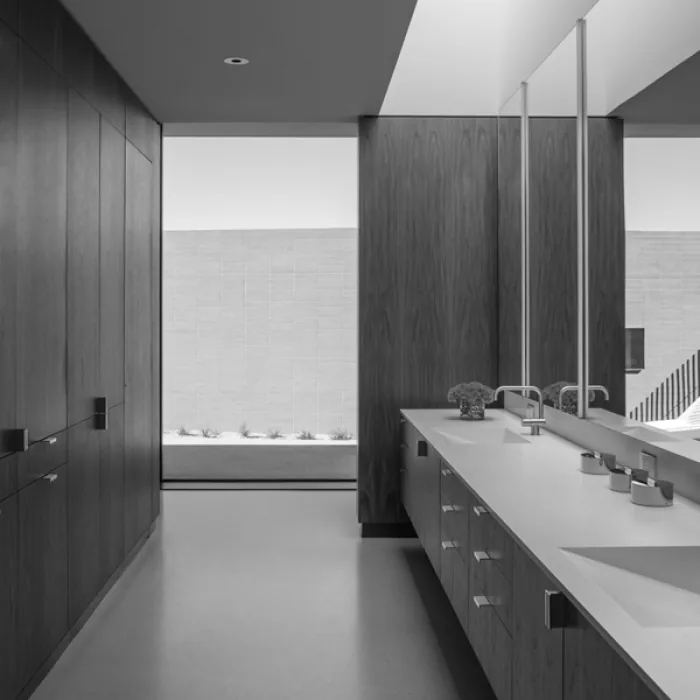 The bathroom features a double vanity with sleek fixtures and a large mirror reflecting minimalist design elements and a desert landscape view.