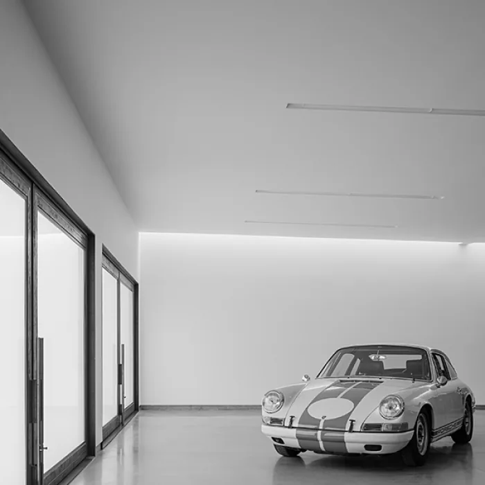 Interior view of a garage featuring a classic car and large glass doors with wood frames.