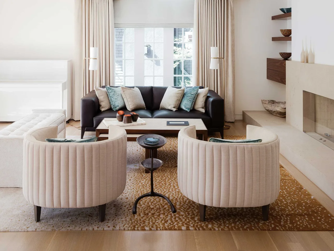 Living room in a modern-style home with curved armchairs and a stone fireplace at Claremont Residence.