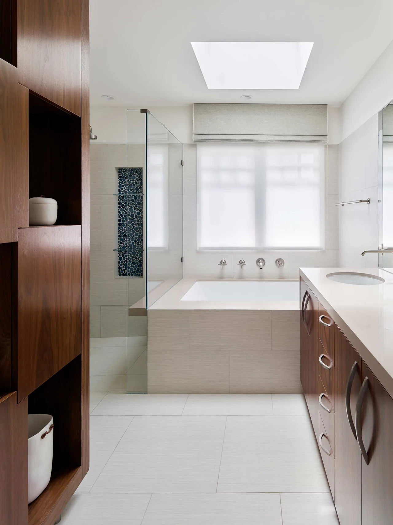 Claremont Residence bathroom shows a built-in bathtub with wall-mounted taps and wood cabinetry vanity under a skylight.
