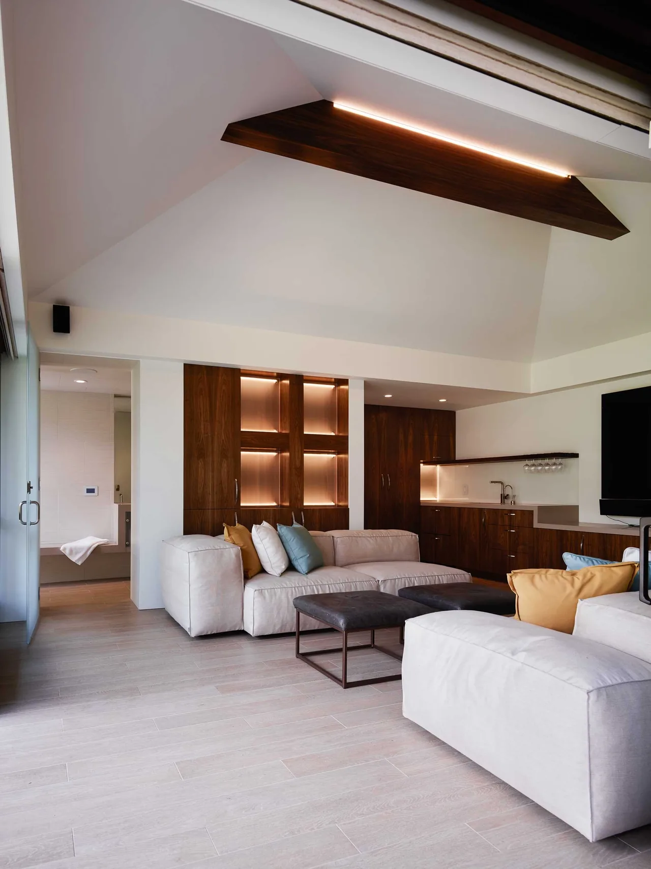 Living room with vaulted ceiling and wood-paneled built-in cabinetry featuring warm lighting.